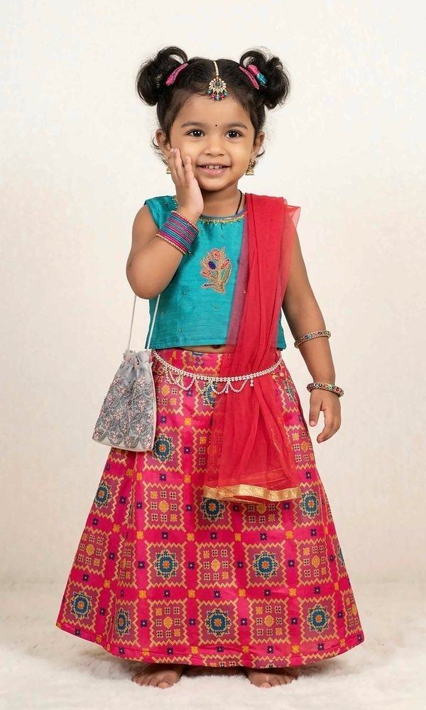 Teal & Pink Patola Lehenga — Teal silk blouse with peacock embroidery, a hot-pink patola-print lehenga and a red net dupatta with gold border — bright and joyful.