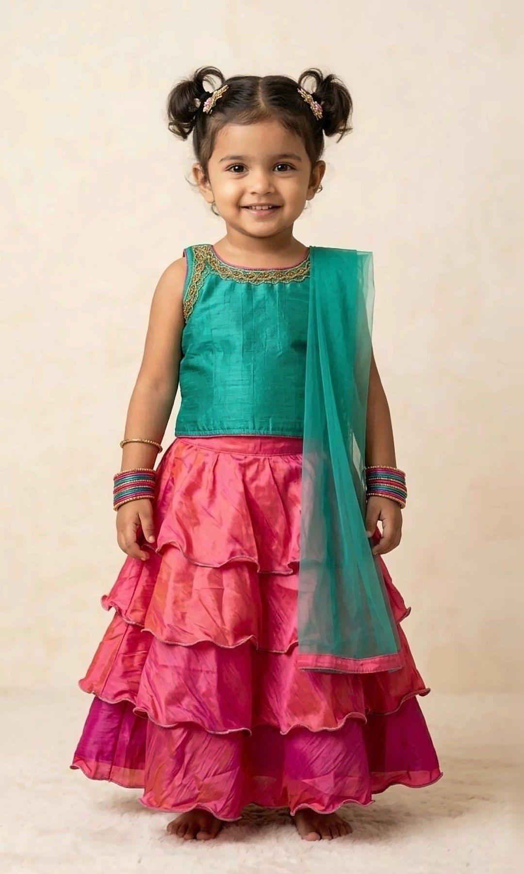 Teal & Pink Ruffle Lehenga — Teal silk blouse with a gold-thread neckline, a three-tier ruffled pink lehenga and a matching teal net dupatta.